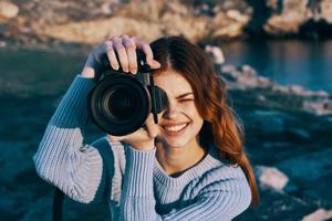 mujer con cámara en naturaleza tomando imágenes de paisaje profesional foto