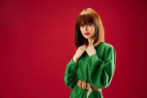 red-haired woman with red lips in a green dress red background photo