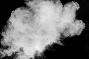 White powder explosion isolated on black background.White dust particles splash. photo