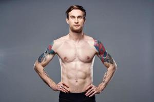 athletic man with pumped up abs tattoos on his arms photo