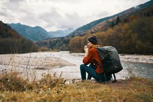 woman travels in the mountains near the river in the meadow in the forest rest relax photo