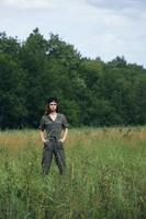 Woman on nature In a green jumpsuit, a black cap, hand pockets fresh air photo