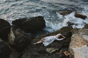 Barefoot woman in a white dress lying on a stone in a white dress nature landscape photo