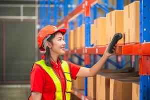 Warehouse worker with bar code scanner checking inventory, Female worker scanning boxes in warehouse rack, Workers working in warehouse photo