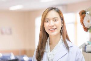 retrato de alegre joven hembra médico posando y sonriente a hospital, médico cuidado de la salud y médico Servicio foto