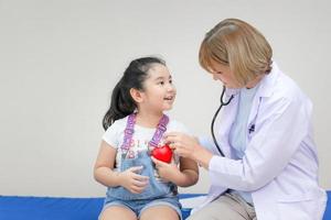 doctora examinando a una niña linda con estetoscopio, niña en consulta con el pediatra. conceptos de salud y medicina foto