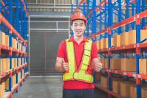 Cheerful male worker in hardhat smiling with giving thumbs up, Warehouse worker working in factory warehouse photo