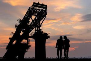 silueta de ingeniero y trabajador con recorte camino comprobación proyecto a infraestructura construcción sitio, construcción sitio a puesta de sol en noche foto