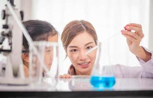 Elementary science class, Cheerful kid girl with teacher scientist in school laboratory, Science laboratory photo