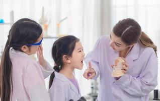 Elementary science class, Cheerful little kids with teacher scientist showing test bottle with chemistry liquid in school laboratory, Science laboratory photo