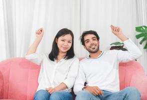 Portrait of happy young couple sitting on sofa ready post holding for your mockup photo