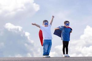 superhéroes niños amigos teniendo divertido exterior, chico y niña con recorte camino jugando al aire libre, hermano y hermana jugando al aire libre foto