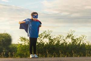 Portrait of adorable kid girl having fun outdoor. Little child girl play superhero photo