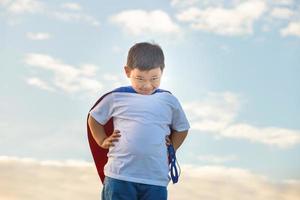 Portrait of adorable kid boy having fun outdoor. Little child play superhero photo