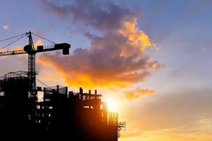 Silhouettes of building construction site with clipping path and construction cranes with blurred sunset background and copy space photo
