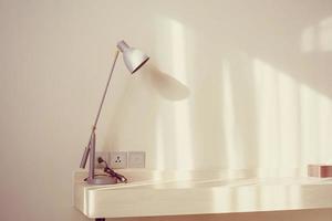 Lamp on wooden desk with copy space on empty wall photo