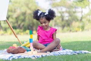 linda pequeño niña jugar juguete a el jardín, niño niña jugando con pequeño de madera juguete al aire libre foto