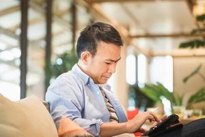 Man drawing a graphics on tablet in a modern coffee shop, Asian man using a tablet, Technology in use concepts photo