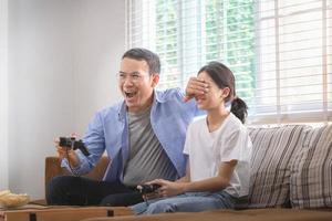 asiático padre y hija jugando vídeo juegos a hogar, personas haciendo ocupaciones y familia conceptos foto