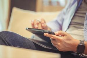 de cerca de manos hombre utilizando un tableta, asiático hombre utilizando un tableta en café comercio, tecnología en utilizar conceptos foto