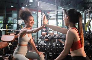 Sport and fitness concepts, Sporty women giving high five to each other while working out together at fitness gym. photo