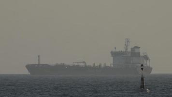 frakt och behållare fartyg på de horisont väntar till docka i de hamn av barcelona med hav gnistrande i de förgrund video