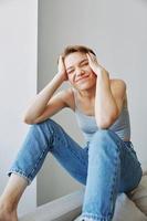 joven mujer con corto Corte de pelo pelo teniendo divertido a hogar en el sofá sonrisa y felicidad, vacaciones a hogar, natural posando sin filtros, gratis Copiar espacio foto