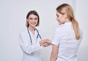 professional doctor nurse shakes hands with a patient and a stethoscope around her neck photo