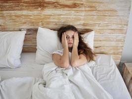 mujer participación su cabeza acostado en cama emociones descontento foto