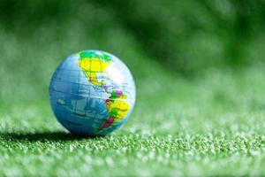 cerca arriba de azul globo en verde césped en verde difuminar naturaleza fondo, tierra día o mundo ambiente día concepto. verde mundo y sostenible conservación de bosque recursos. foto