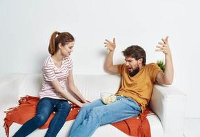 Fun man and energetic woman watching TV on the couch popcorn in a plate family communication photo