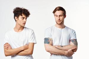 two men in white t-shirts stand side by side cropped view studio friendship photo