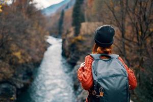 mujer con mochila admira el río en el montañas naturaleza viaje foto