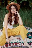 hermosa joven niña de cerca mira dentro el cámara en un sombrero vistiendo un eco hippie al aire libre, hermosa sonrisa con dientes en el puesta de sol ligero foto