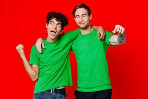 Two cheerful friends hug green t-shirts emotions communication red background photo