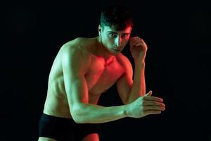 sexy athletes with pumped up arm muscles posing on a black background and bright falling light photo