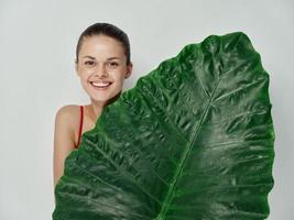 cheerful woman covers bodies with green leaf smile light background photo