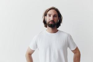 contento hombre escuchando a música y sonriente en un blanco camiseta en un blanco antecedentes contento foto