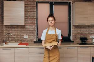 un ama de casa en un delantal en el cocina corte tablero con cuchillo tareas del hogar casa concepto foto