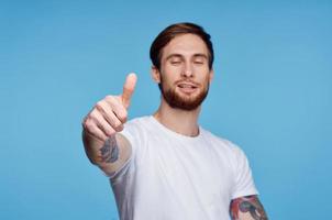 man in white t-shirt showing thumb up blue background studio photo