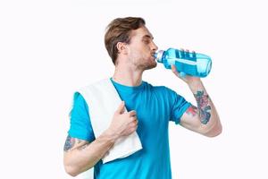 man athlete drinks water from a bottle on a white background and a towel on his shoulder photo