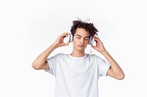 guy with curly hair and headphones white t-shirt light background close-up cropped photo