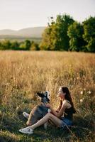 Woman sitting in field with dachshund dog smiling while spending time in nature with friend dog in autumn at sunset while traveling photo