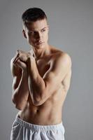 guy with athletic physique joined hands near shoulder on gray background cropped view photo