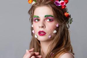 Close-up face of a beautiful girl with fairytale make-up. Spring girl. Gorgeous beauty with extended eyebrows and eyelashes. Natural cosmetics concept. The image of spring. photo