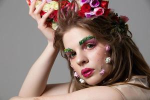 Portrait of a beautiful girl with bright spring make-up. Summer girl in flowers. The face of a gorgeous beauty with extended eyebrows and eyelashes. Natural cosmetics concept. photo