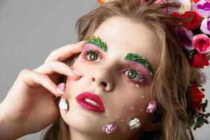 Portrait of a beautiful girl with spring make-up. Summer girl. The face of a luxurious model in flowers. The concept of eyebrow and eyelash extensions. photo