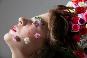 Face in profile of a girl close-up in floral makeup. Spring or summer beauty. Woman with flowers on her face. photo