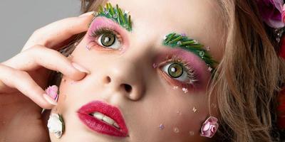 Portrait of a beautiful girl with creative make-up. Summer girl. The face of a luxurious model in flowers. The concept of eyebrow and eyelash extensions. photo
