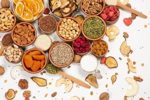 Healthy vegetarian food concept. Assortment of dried fruits, nuts and seeds on white background. Top view. photo